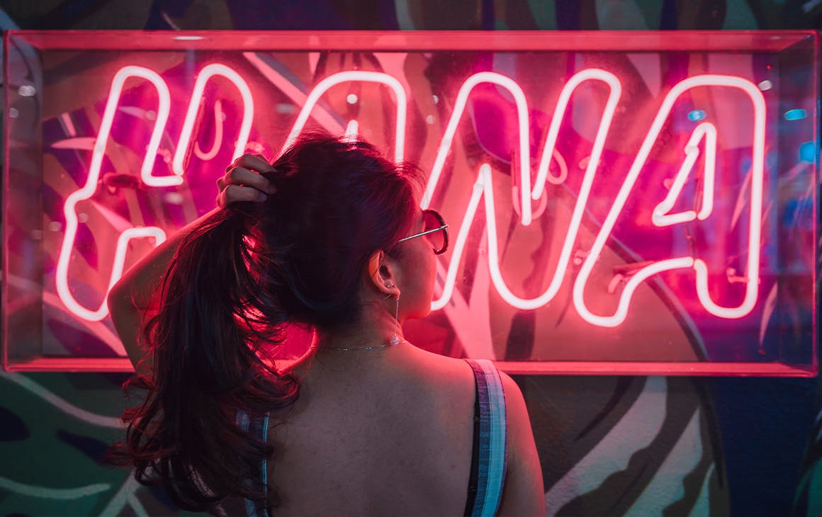 A woman with a ponytail in front of a neon sign