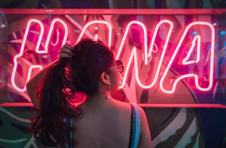 A woman with a ponytail in front of a neon sign
