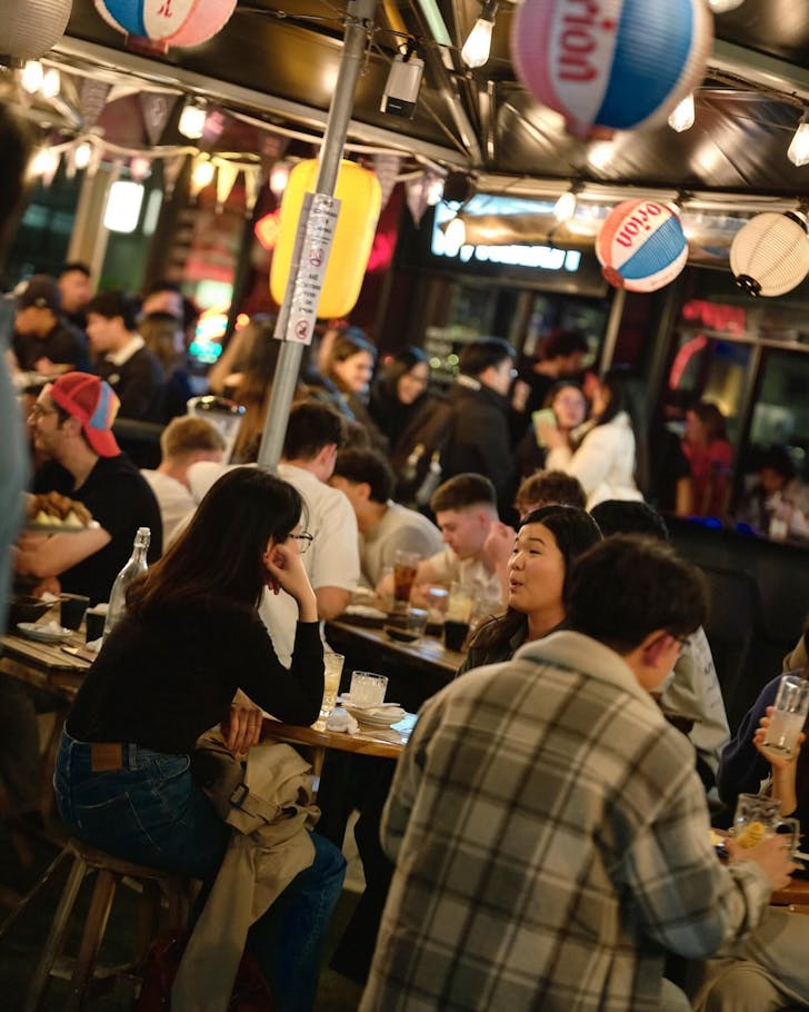 people enjoying japanese food and drinks under lanterns at nakano darling in haymarket