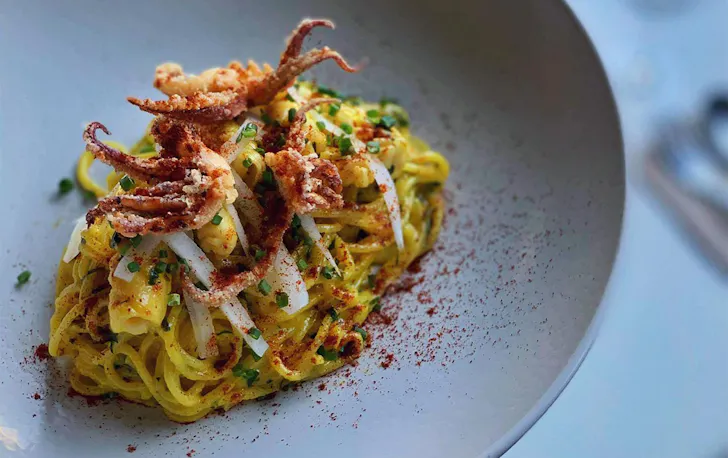 a plate of spaghetti topped with crispy octopus