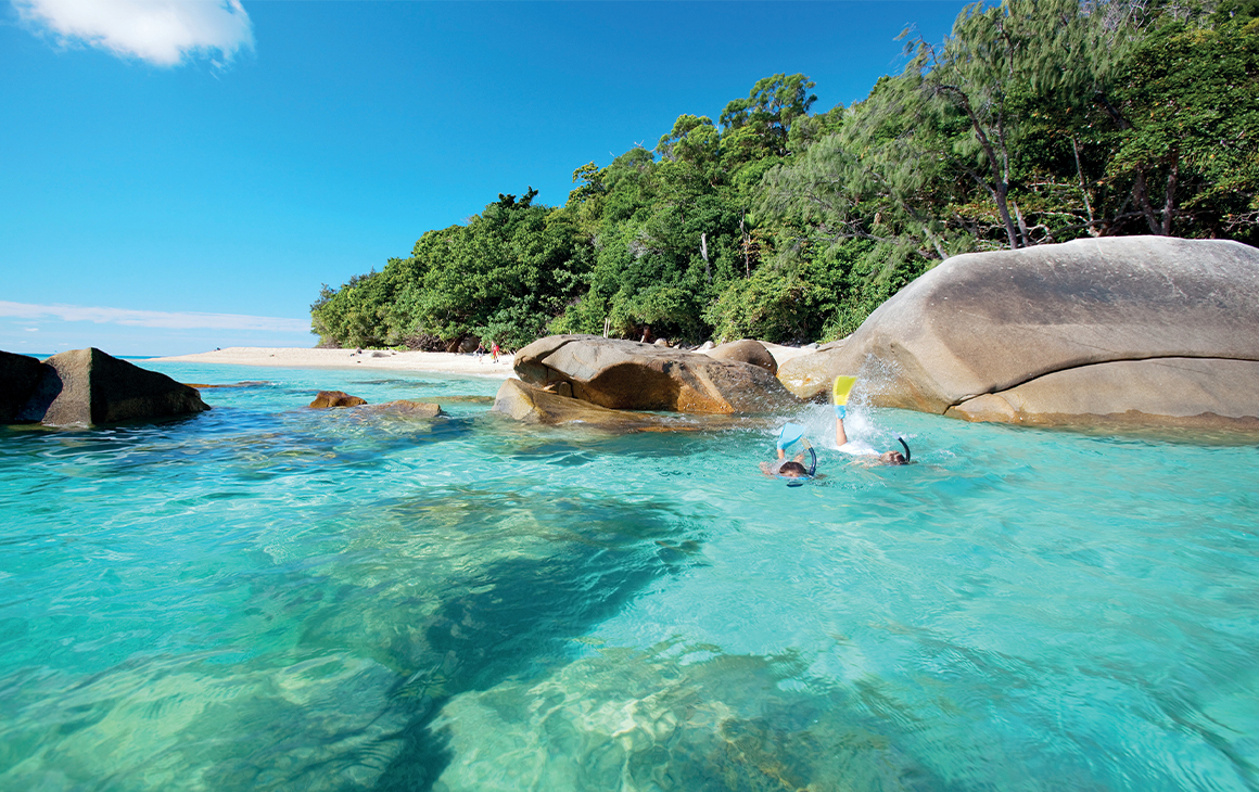 a person snorkeling in blue water off nudey beach on Frizroy Island in Queensland