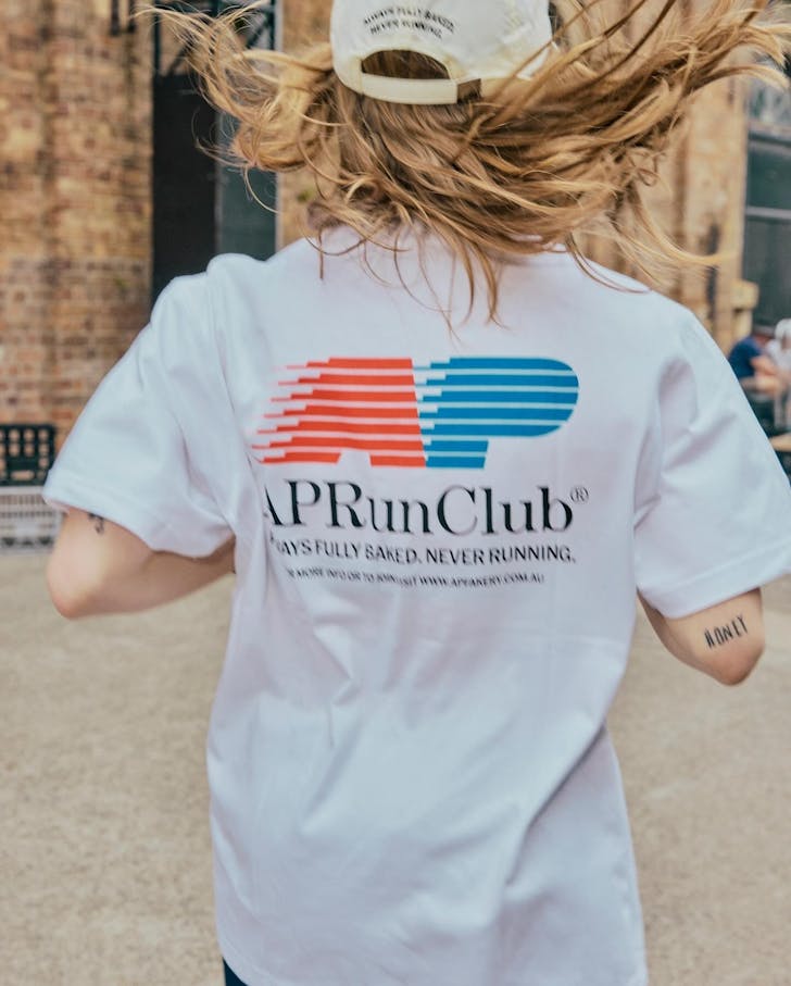 a woman runs in an a.p bakery run club t shirt