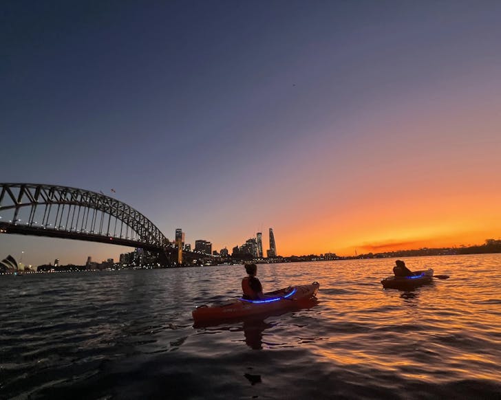 people watch the sunset over sydney harbour from kayaks