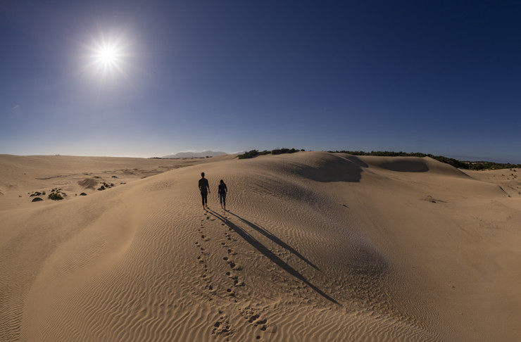 The sun shining on a hiker walking through the Big Drift sand dunes in Victoria.