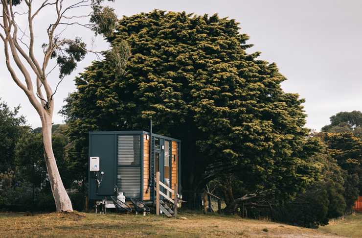 A tiny house on a lush green hill.