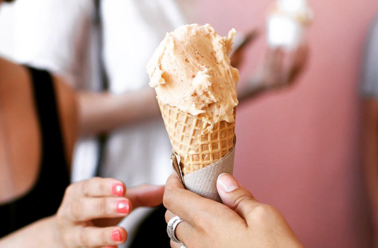 A person wearing a ring and gloss nails holding up a cone of one of the best ice cream Melbourne has. 