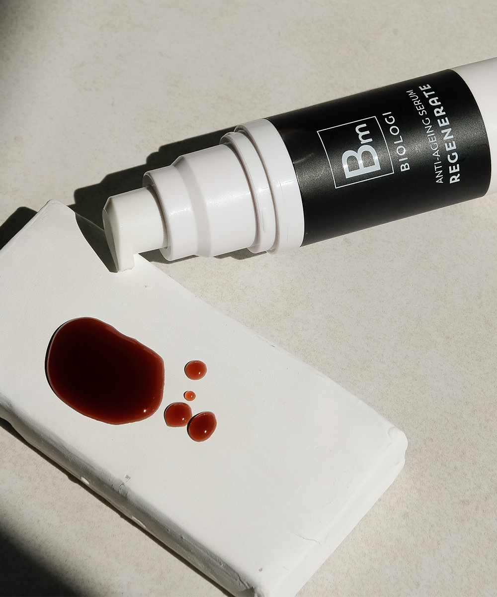 a bottle of serum next to a face wipe with drops of serum on it