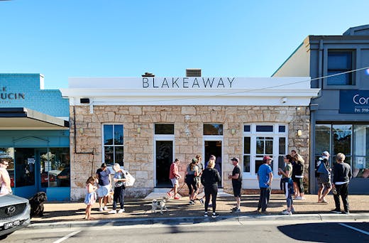 People standing out the front of a cafe with the signage 