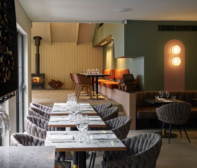 The dining room at Blaq restaurant, complete with plush chairs and an open fireplace.