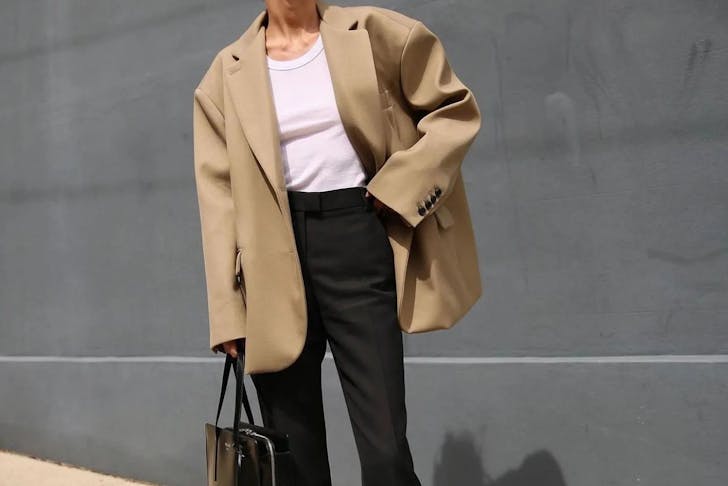 A person wearing an oversized beige blazer. 
