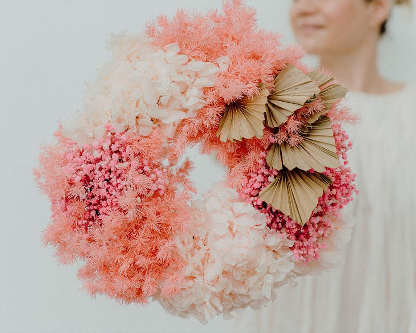 A person holds a round assortment of flowers from Blush.