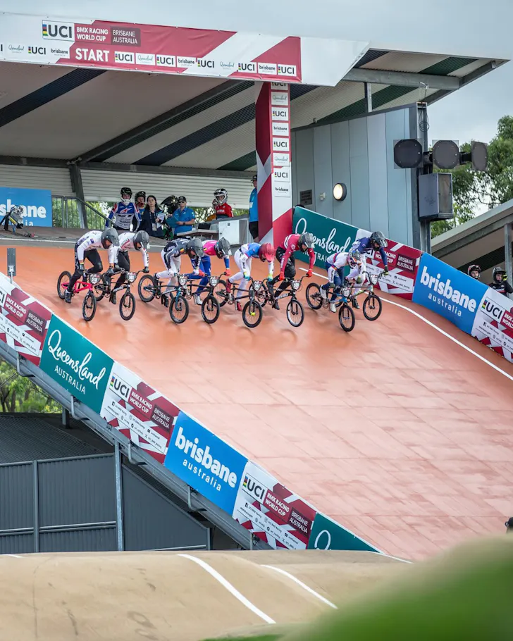 A row of BMX racers hurtling down a hill at the starting line of the BMX World Championships.