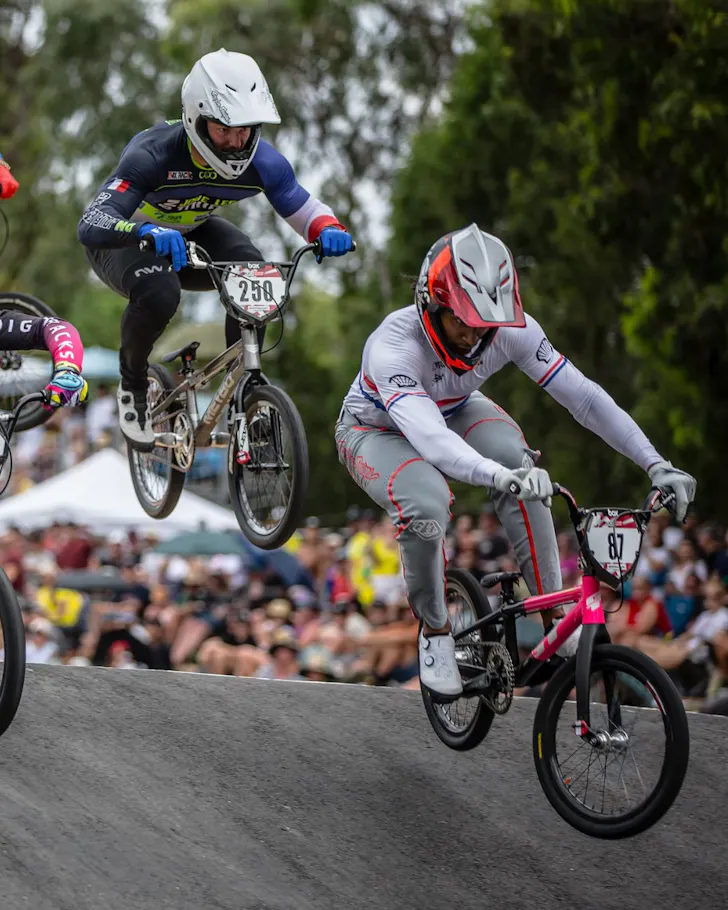 Two BMX riders go wheel-to-wheel on the track. 