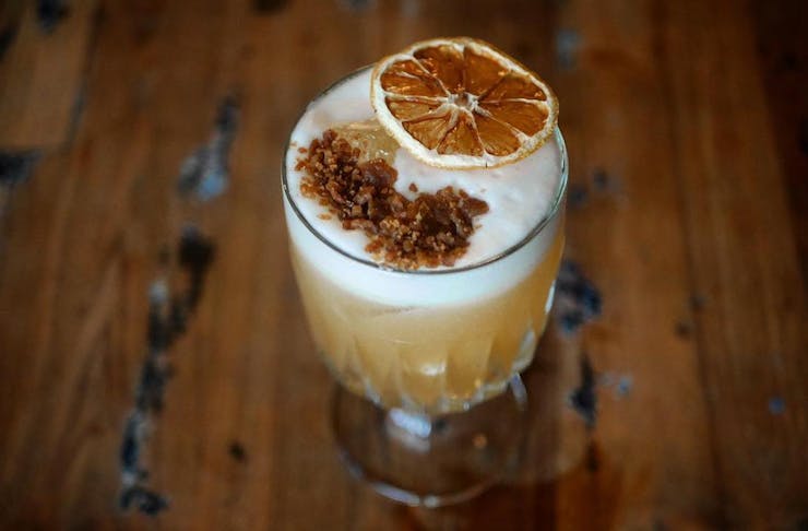 an amaretto sour with hazelnut praline and a dried slice of lemon on top