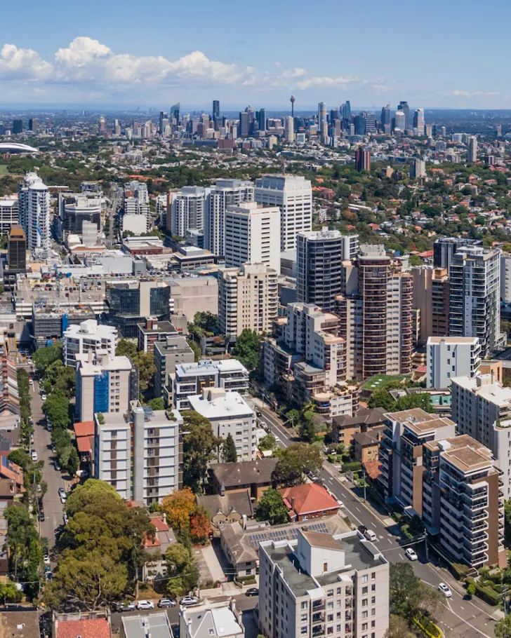 Aerial view of Bondi Junction's skyline, with apartment towers and commercial buildings stretching toward the Sydney CBD in the distance.