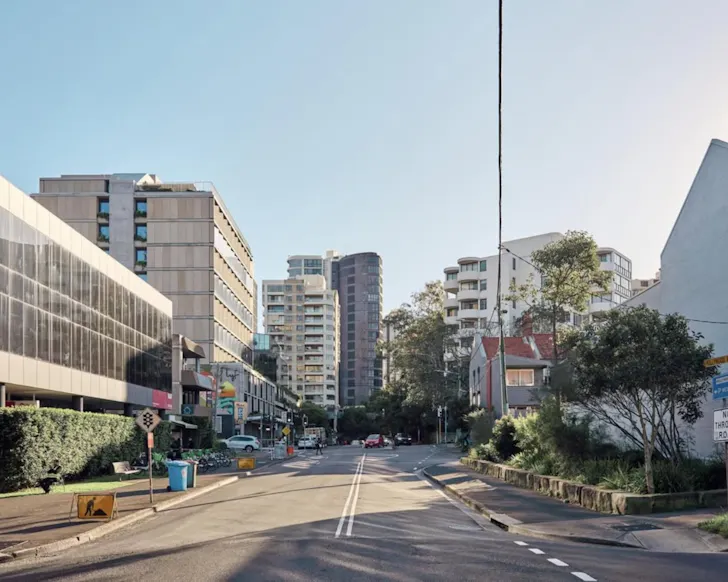 Streetscape view of Bondi Junction, showing a mix of apartment towers, commercial buildings and residential homes lining a quiet urban street.