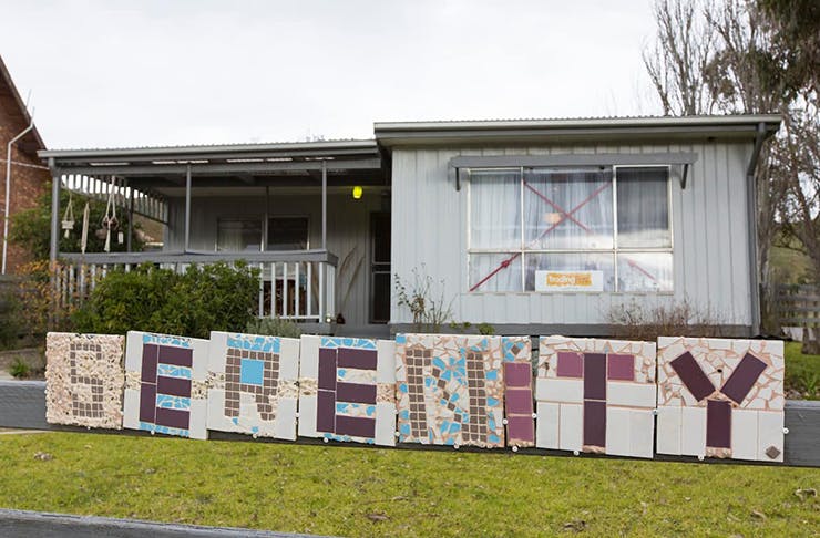 An old house with a tiled sign out the front reading 