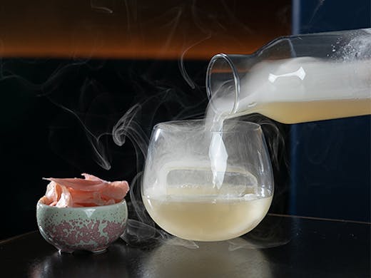a smokey cocktail being poured into a glass