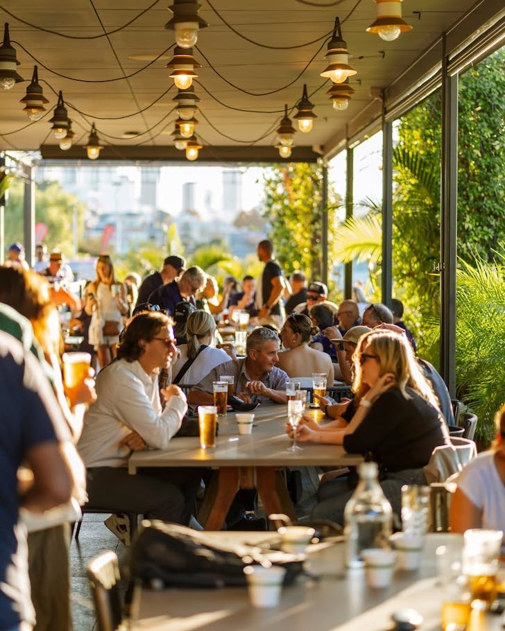 âPeople enjoying drinks and food at a sunny outdoor terrace at The Camfield in Perth. The lively atmosphere captures friends gathering for a relaxed weekend bottomless brunch or afternoon session.â