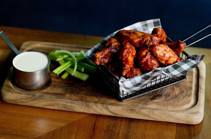 a metal basket filled with saucy wings