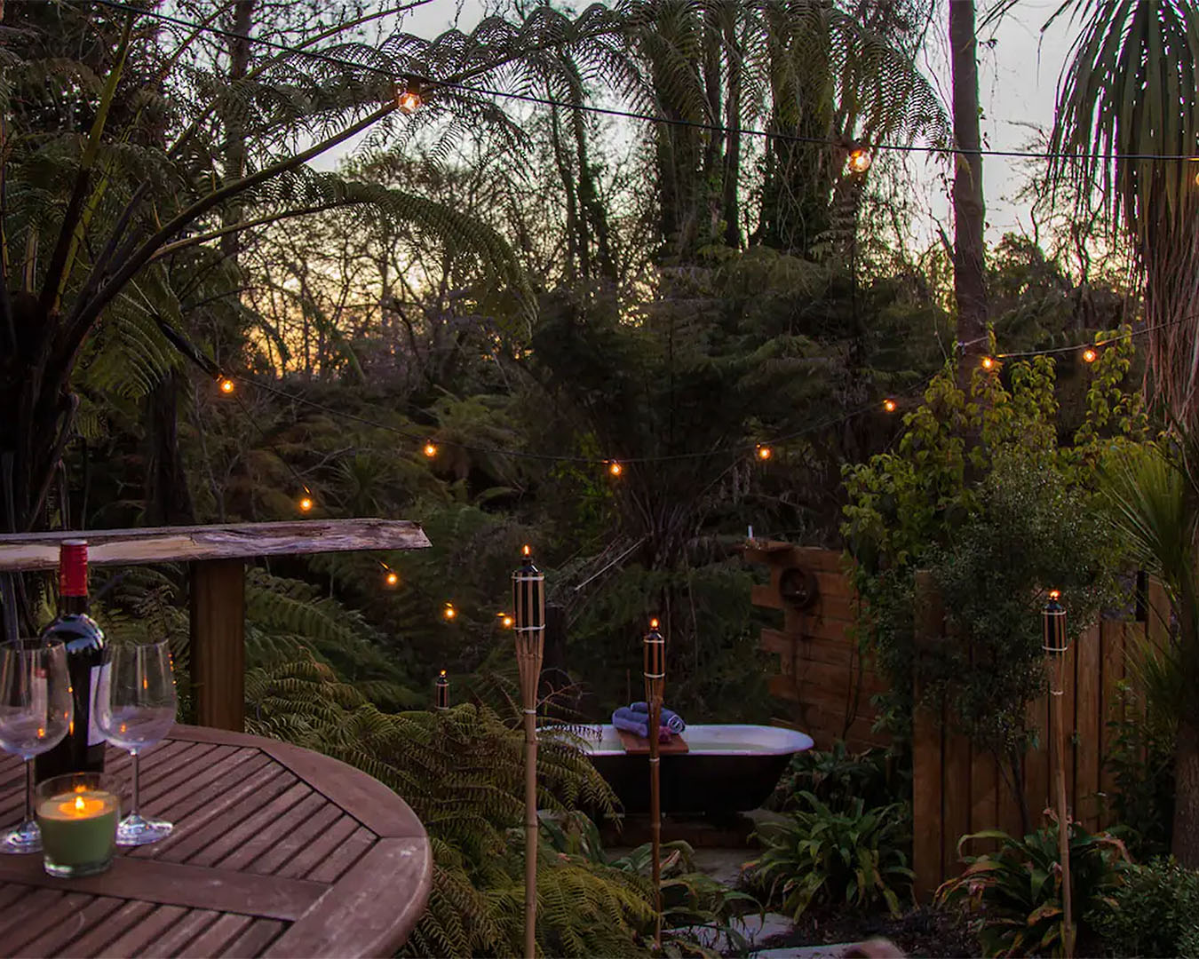 A stunning garden lit by fairy lights and tiki torches in the garden, with an outdoor bath with running hot water. No wonder this is one of the best Airbnbs in NZ with an outdoor bath.