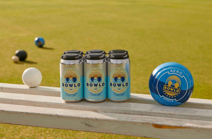 A six-pack of Bowlo Draught with a bowling green in the background. 