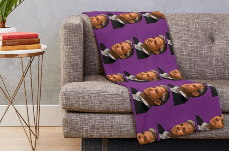 A throw rug laying on a couch with Prof. Brett Sutton's face on it.
