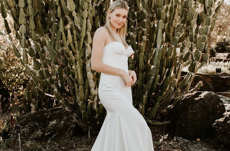 a woman in a wedding dress standing in front of a large cactus