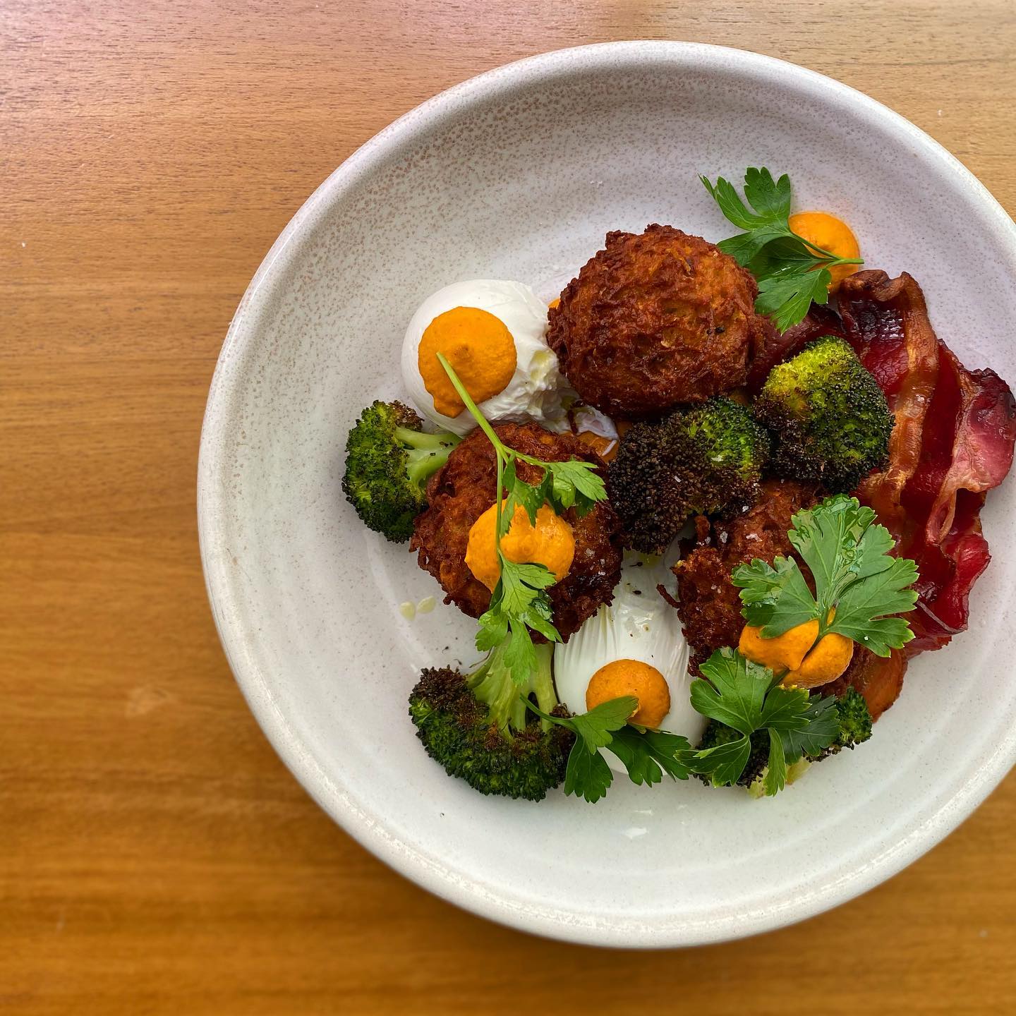 a plate of corn fritters with broccoli and bacon