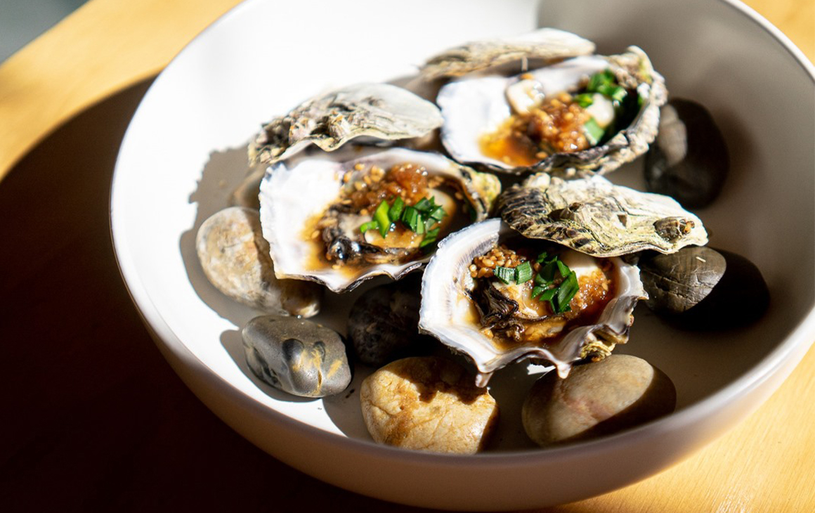 A bowl of baked oysters with garnish