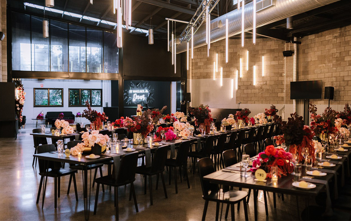an industrial space filled with tables adorned with flowers at a a wedding venue in brisbane