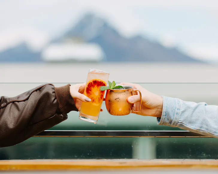 A close up of two people cheersing tapped cocktails