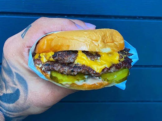 a hand holding a burger 