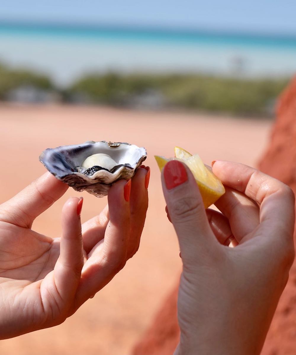 person holding an oyster and a lemon in Broome