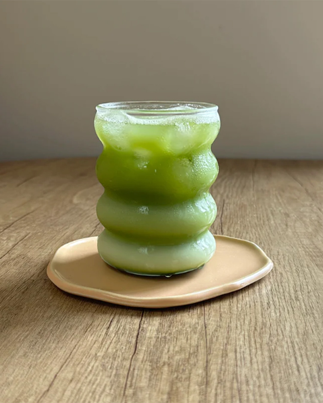 A green ice cold matcha in a wavy cup.