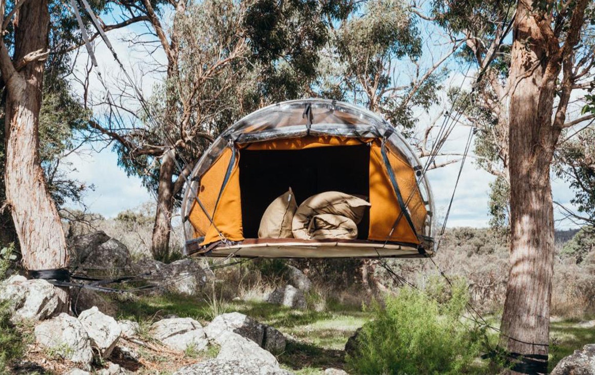 a small tent hung between trees