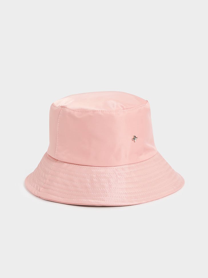 A pink bucket hat with a silver cross logo on the front.
