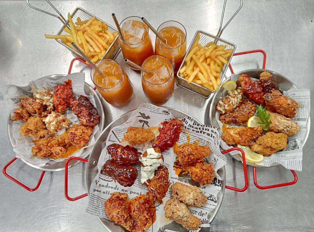 a table full of fried chicken, fries and drinks