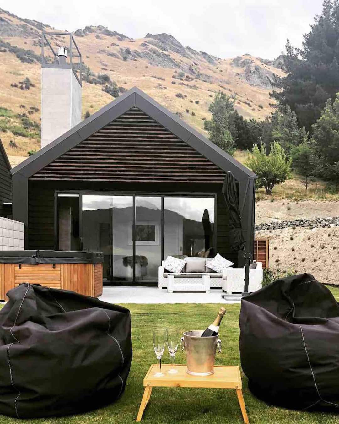 A modern home with a hot tub and bean bags on the lawn