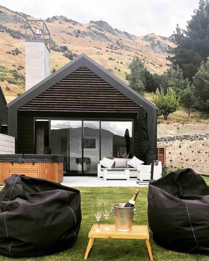 An exterior view of Lake Hayes Suite with hot tub at the front and mountains behind, one of the best NZ Airbnbs