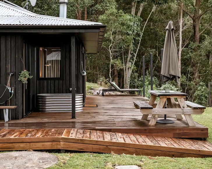 An exterior view of Donnington Ridge Eco Cabin Airbnb near Brisbane Queensland with an outdoor bath on the deck