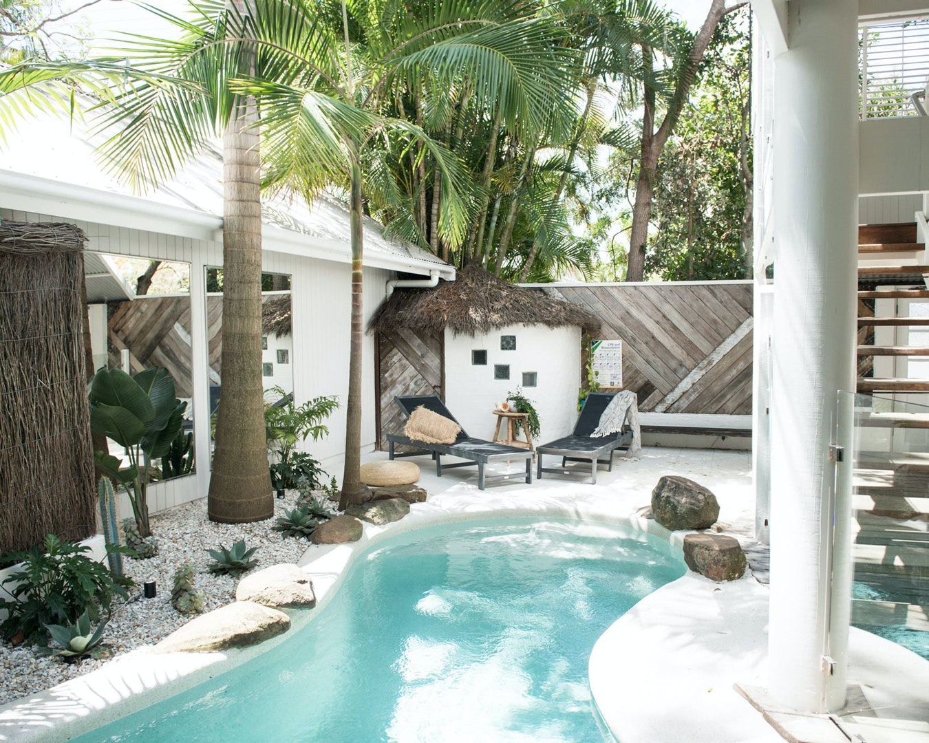 a tulum-style pool surrounded by palms