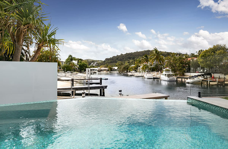 A crystal -clear pool in the sunshine, situated by a waterway with boats passing by.