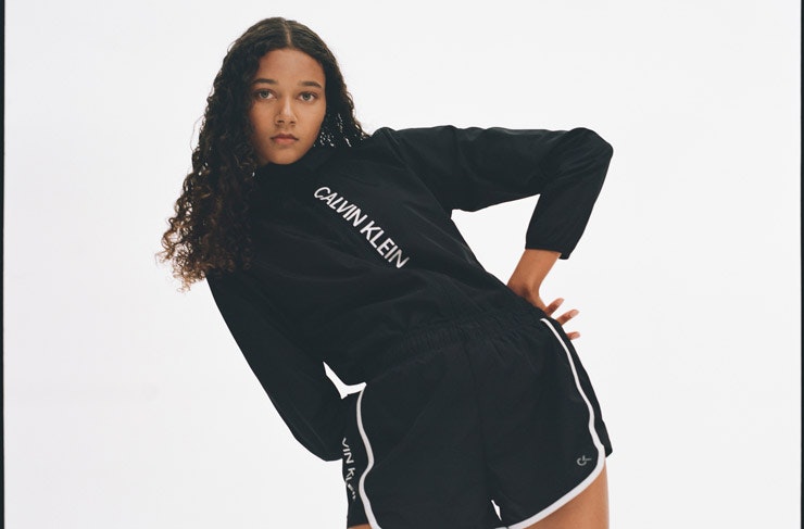 A model wearing a black and white Calvin Klein hoodie and black running shorts. 