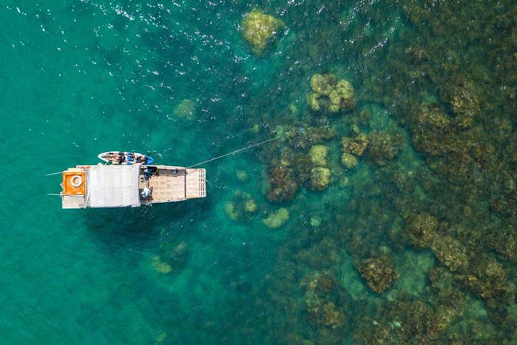 a drone shot of a small boat over a reef