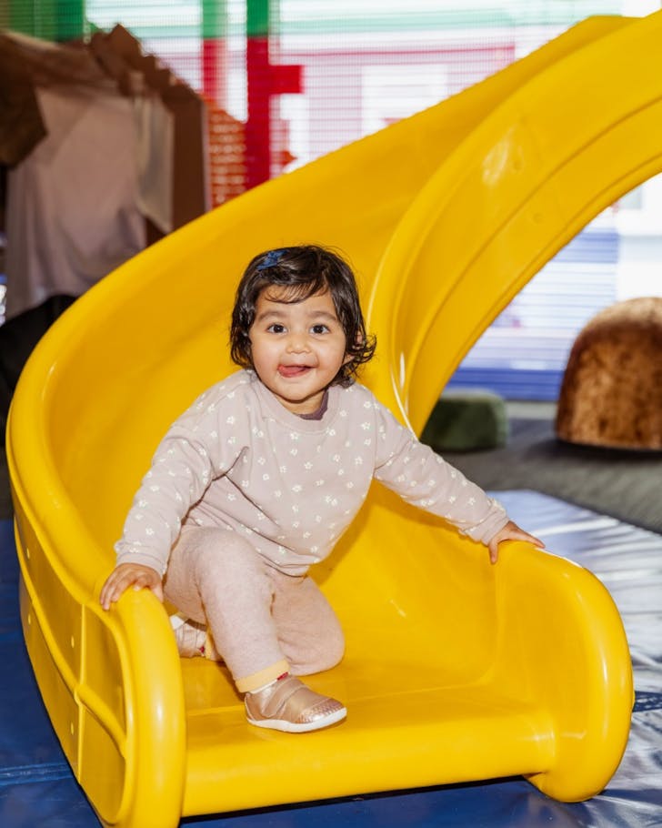 toddler slides down a slide at capital e