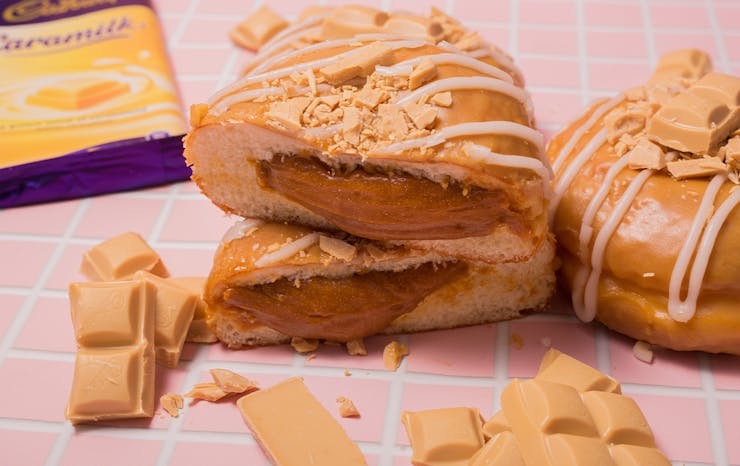 a doughnut filled with caramel, cut in half and stacked, caramilk chocolate scattered around