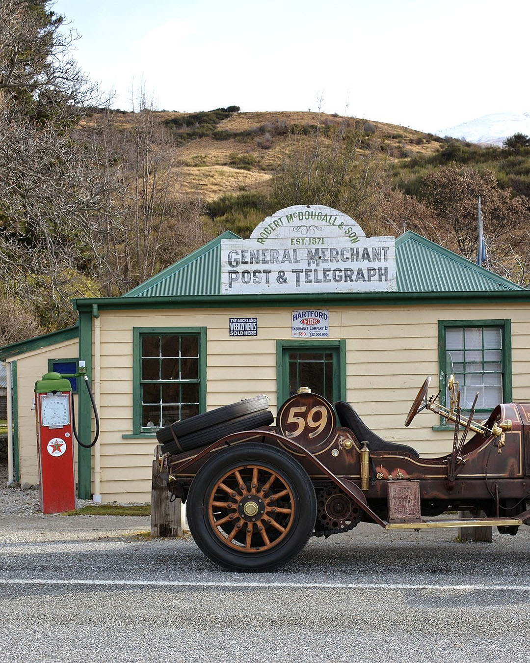 A vintage car in front of an old fashioned post and telegraph shop.