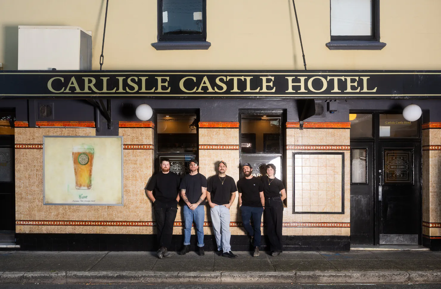 four people posing outside of a pub