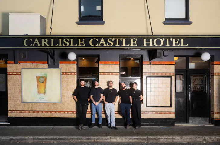 four people posing outside of a pub